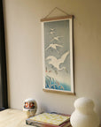 Descending egrets in snow – Ohara Koson art print 30 x 60 cm on a wooden poster hanger in an interior